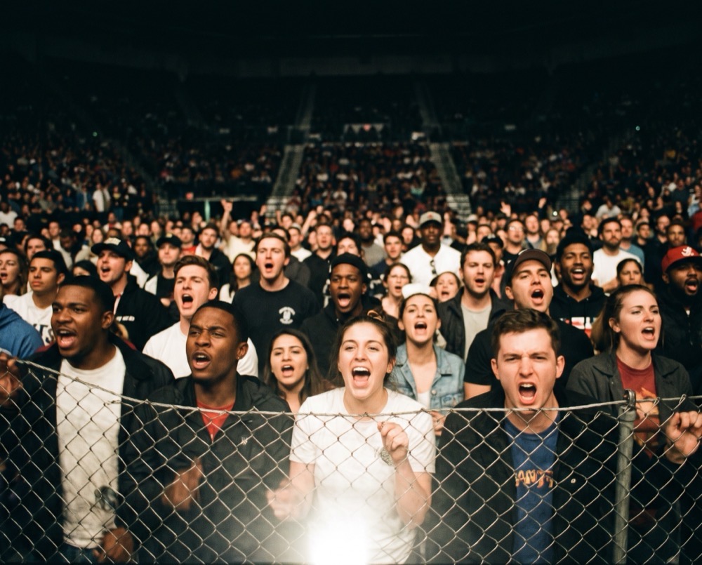 Crowd faces at the fence, mid-shout