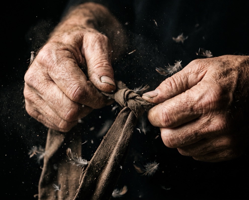 Detail shot of hands, feathers, and the bell